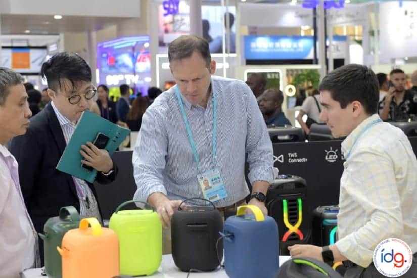 Compradores internacionales evaluando parlantes portátiles en la Feria de Cantón