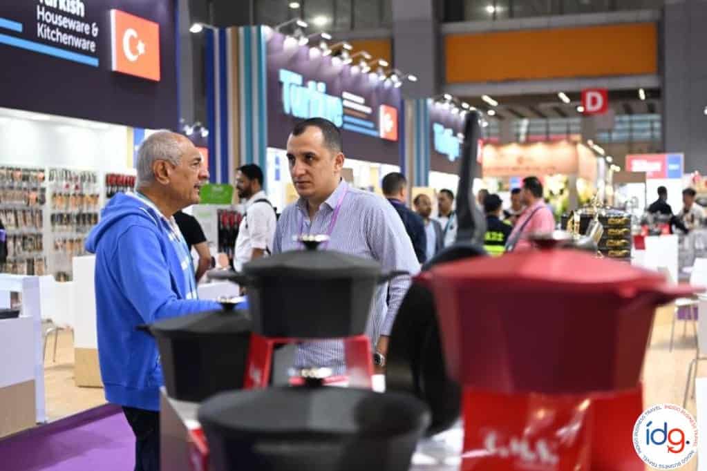 Conversación entre expositores en el pabellón de Turquía durante la Feria de Cantón, frente a utensilios de cocina